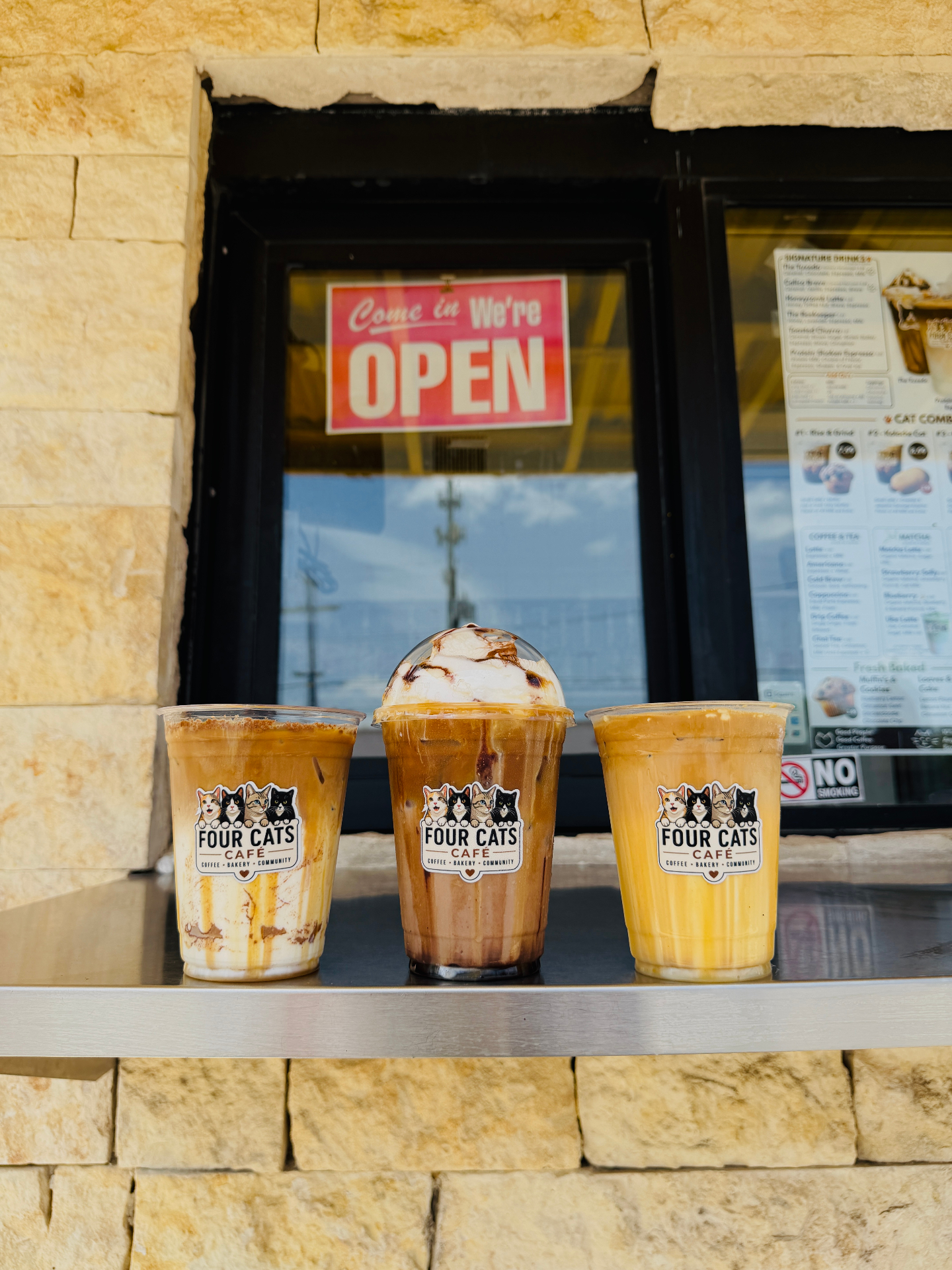 Signature Four Cats Café drinks lined up at the drive-thru window